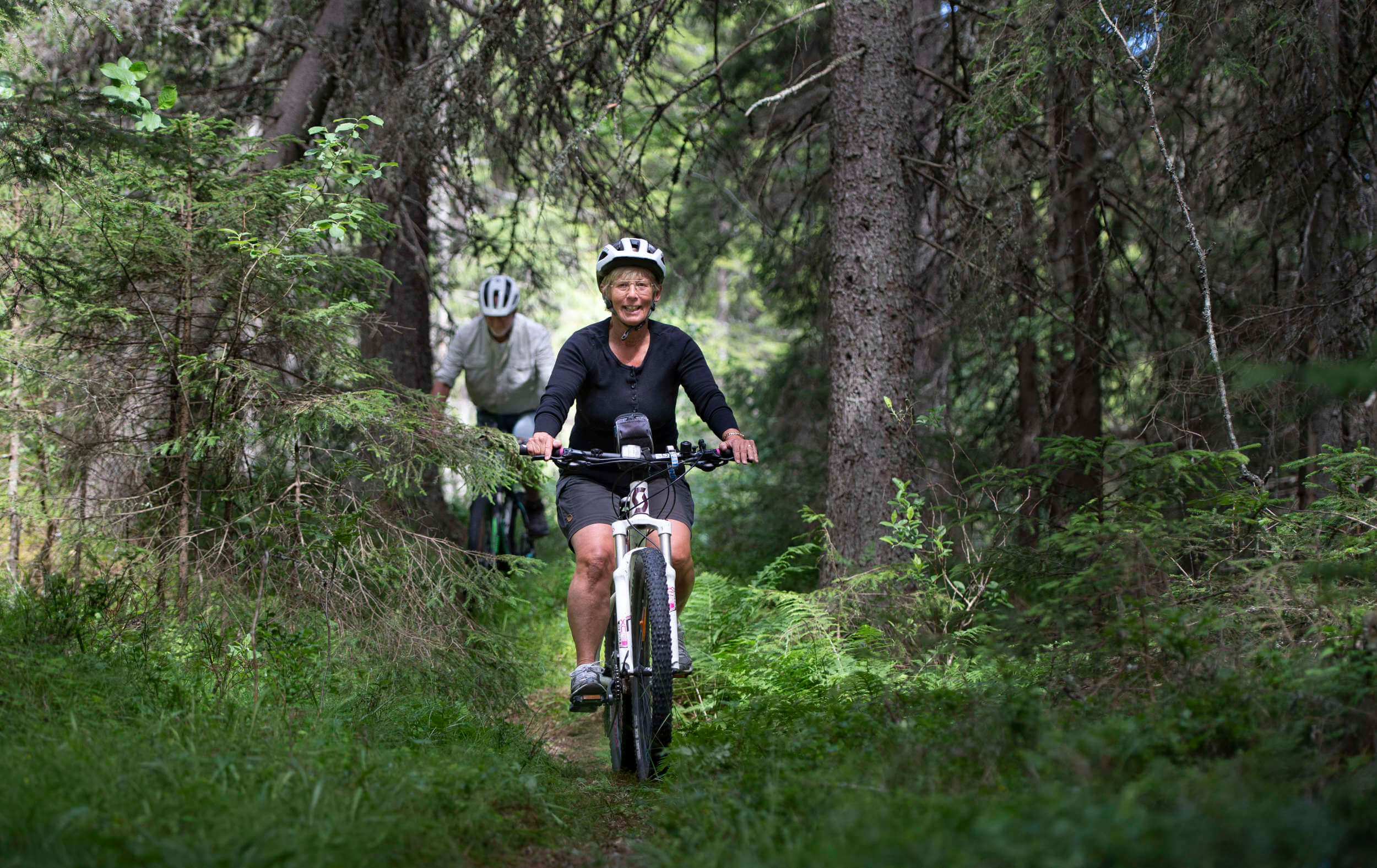 Två personer cyklar i skogen
